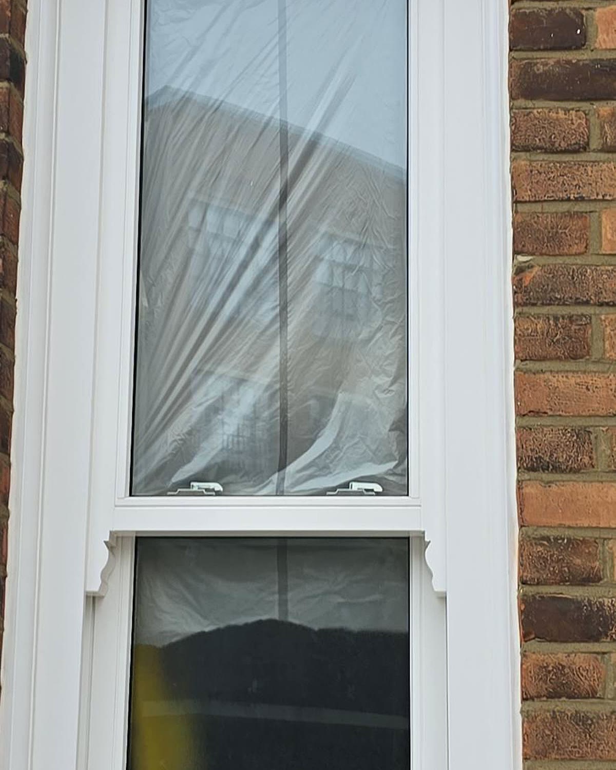 Timber box sash window installed in a London brick terrace, protective film still on the glass