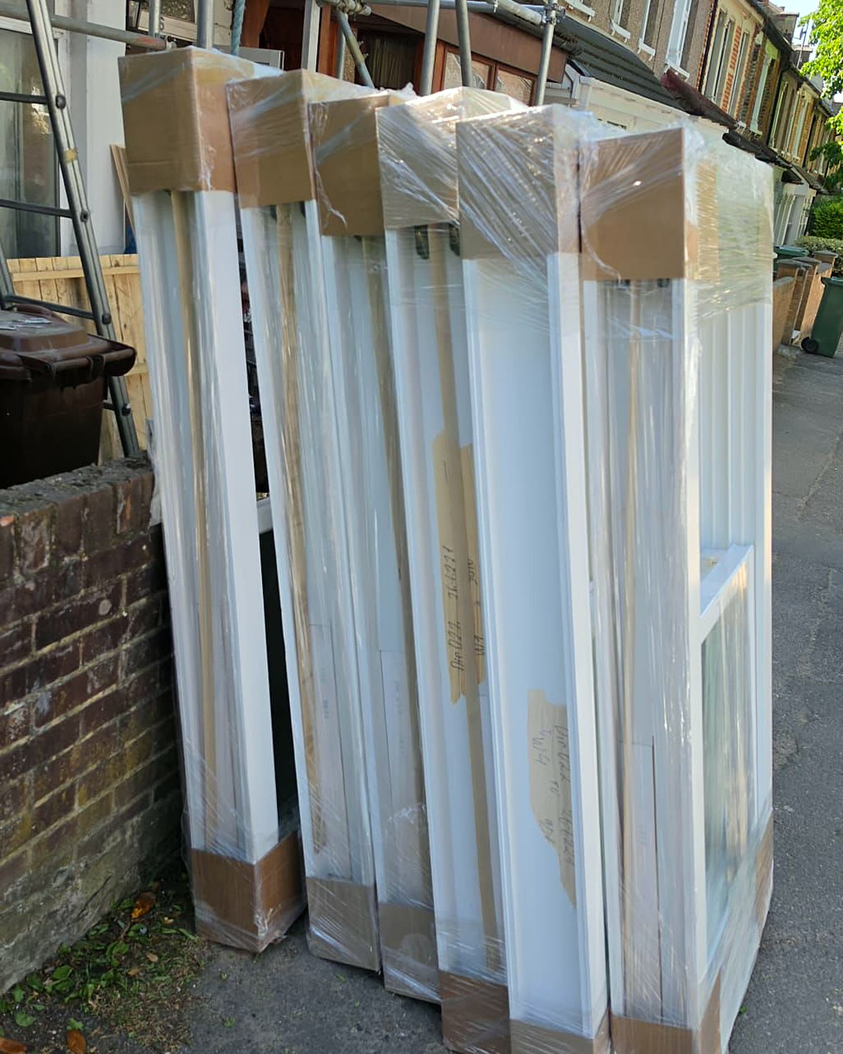 Wrapped timber sash windows standing in a London terrace street with scaffolding behind
